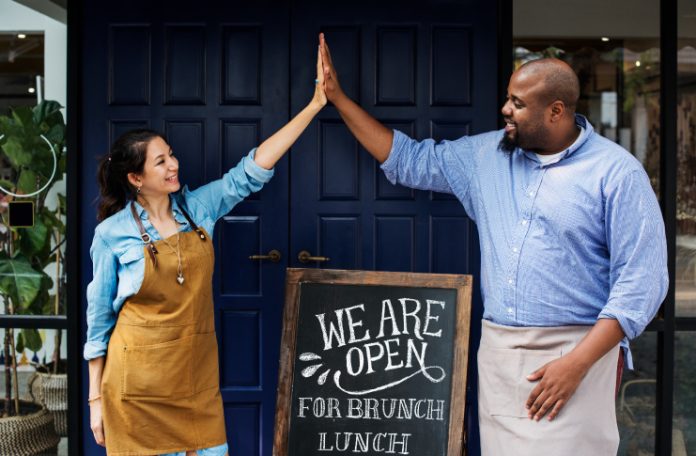 A woman and a man high-fiving after successfully starting a restaurant