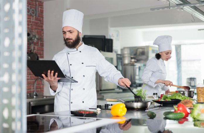 Cloud Kitchen Chef cooking and holding a tablet