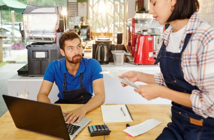 A man and a woman calculating the expenses of their restaurant.