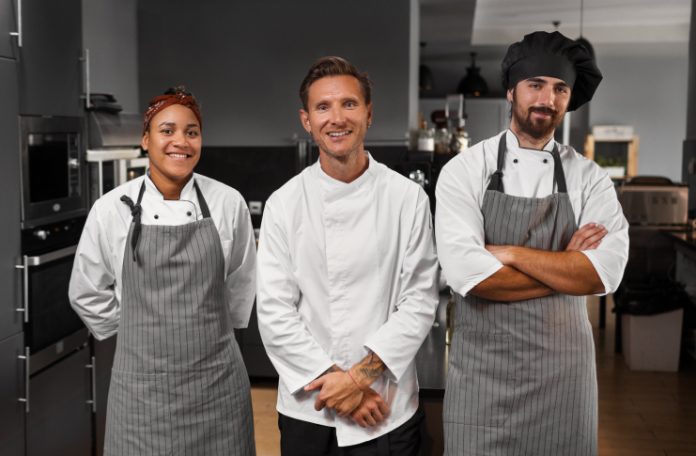 Three kitchen staff members posing for a photograph in a restaurant's Kitchen