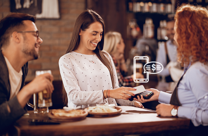 Woman using smartphone to pay bill in a restaurant