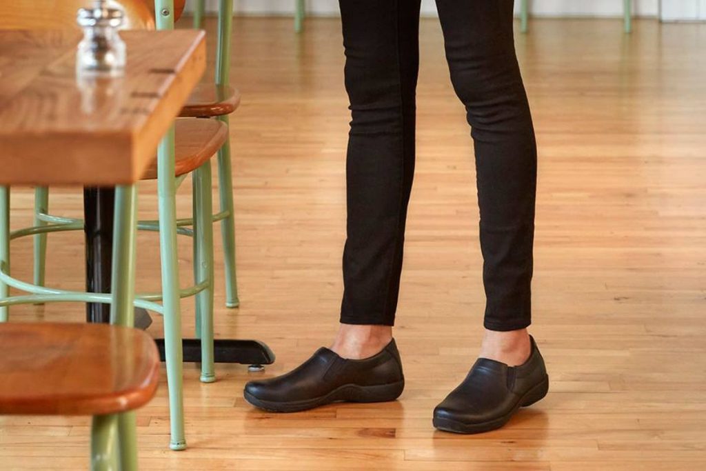 A woman wearing Dansko shoes in a restaurant