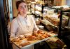 9 Essential Bakery Business Tips That Will Make Your Bakery a Success In 2023 Woman holding a tray of baked food items in a bakery
