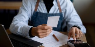 Top Restaurant POS Features To Look For In 2024 Restaurant Staff holding a bill receipt