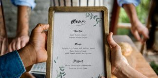 9 estrategias de fijar el precios del menú de restaurante para maximizar la ganancia 2 person holding and looking at a restaurant menu