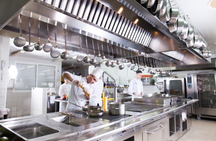 A chef working in a well equipped fast food restaurant kitchen