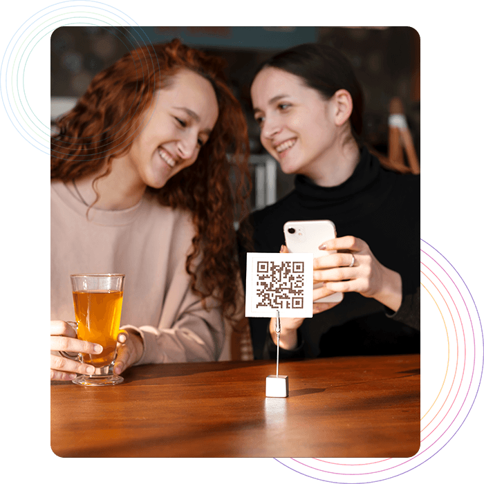 Two female customers placing order in a restaurant using QR code تجربة محسنة للضيوف مع تناول الطعام بدون تلامس