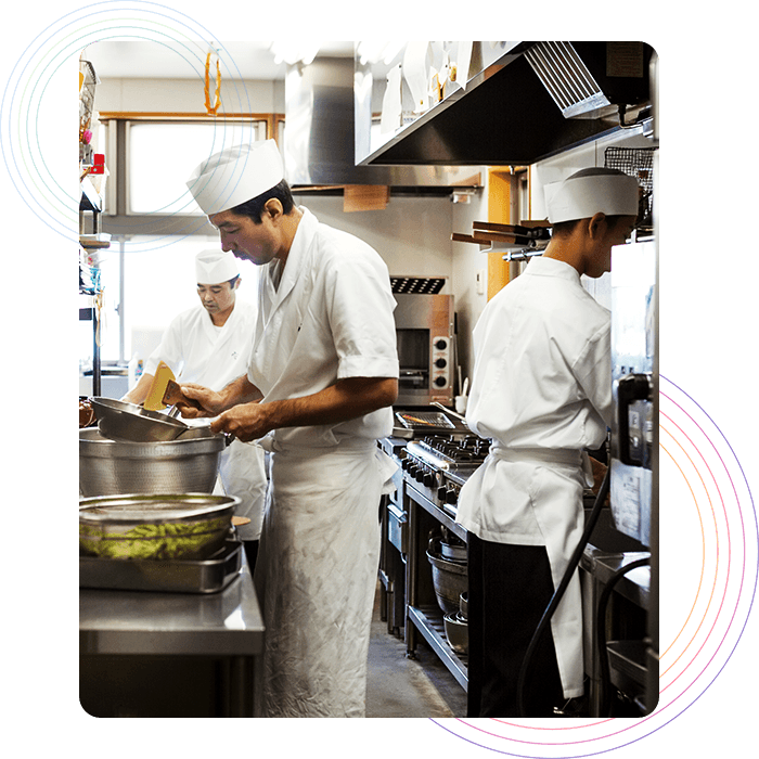 Three chefs preparing orders in a restaurant kitchen