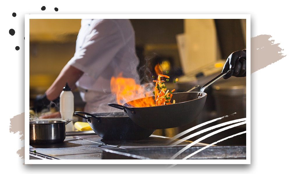 Chef tossing veggies in flaming pan