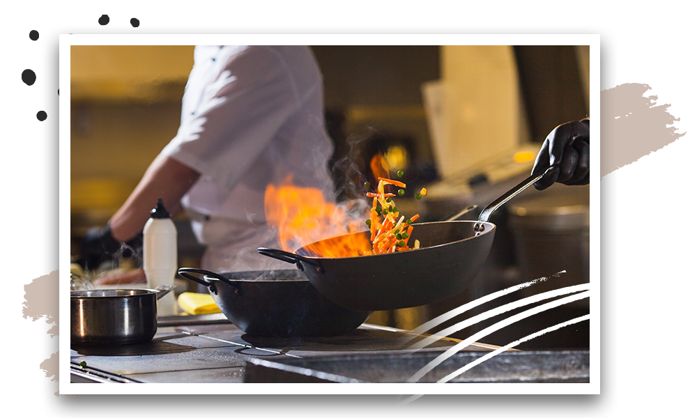 Chef tossing veggies in flaming pan